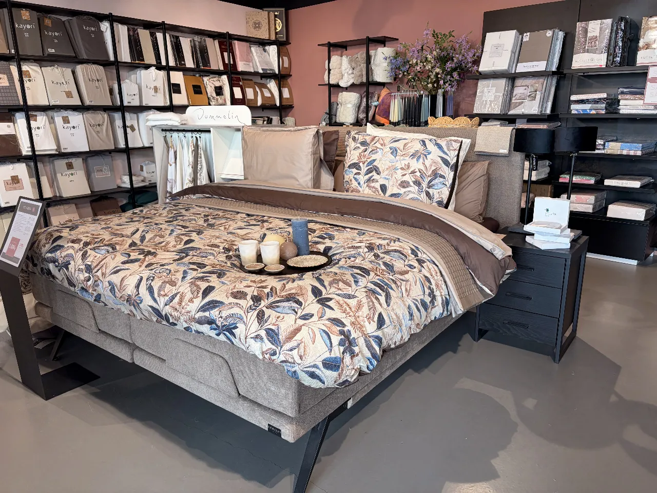 Een bed met bloemenbeddengoed voor de wand met linnen