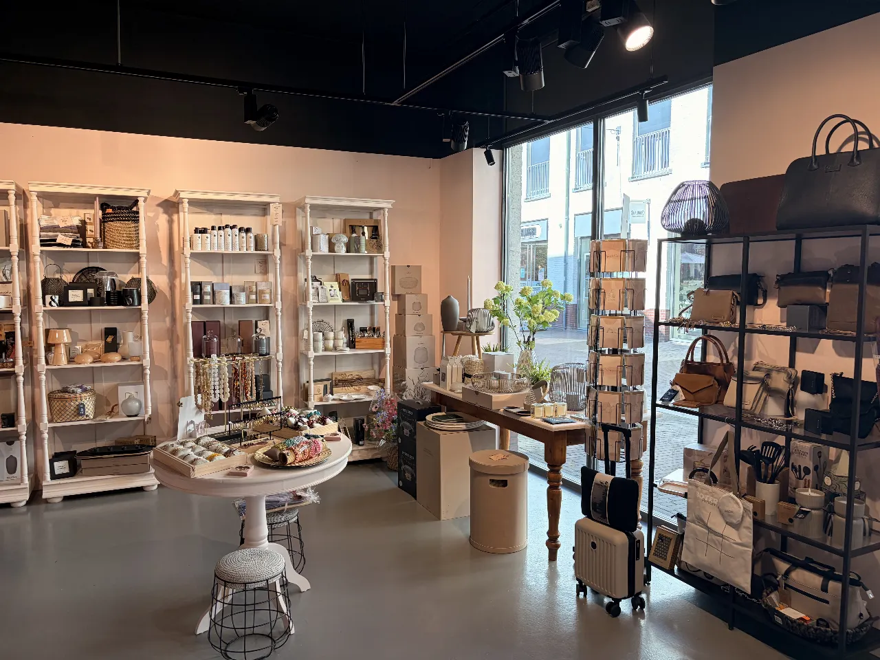 Leren tassen in het zwarte rek naast de kaarten en woonaccessoires