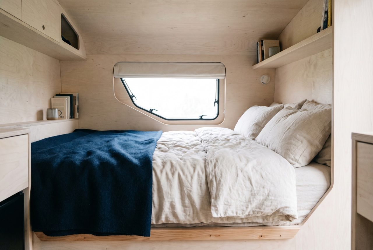 Bedstee in een camper met een op maat gemaakt matras in de houten bak.